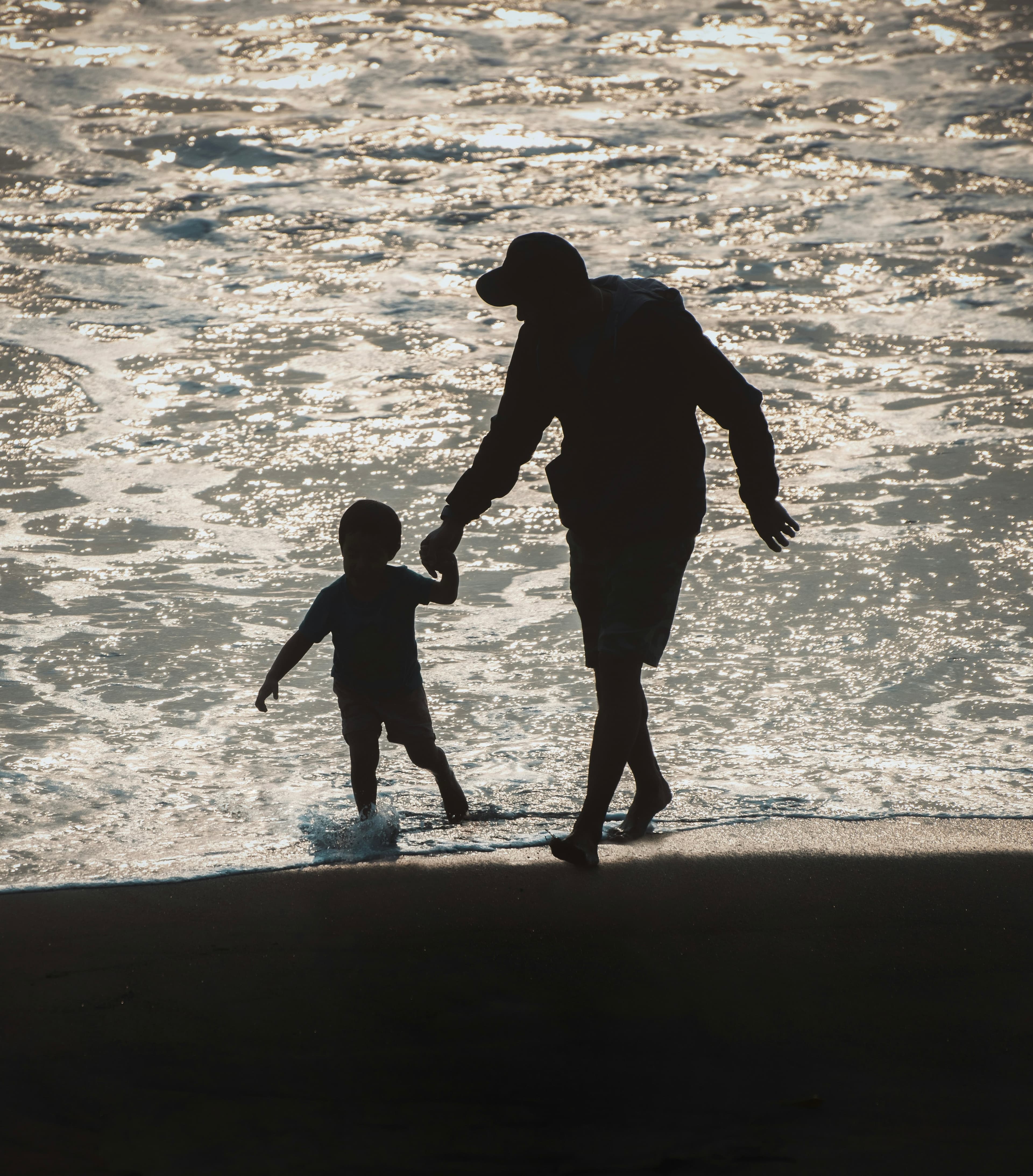 A parent and child walking along a shoreline